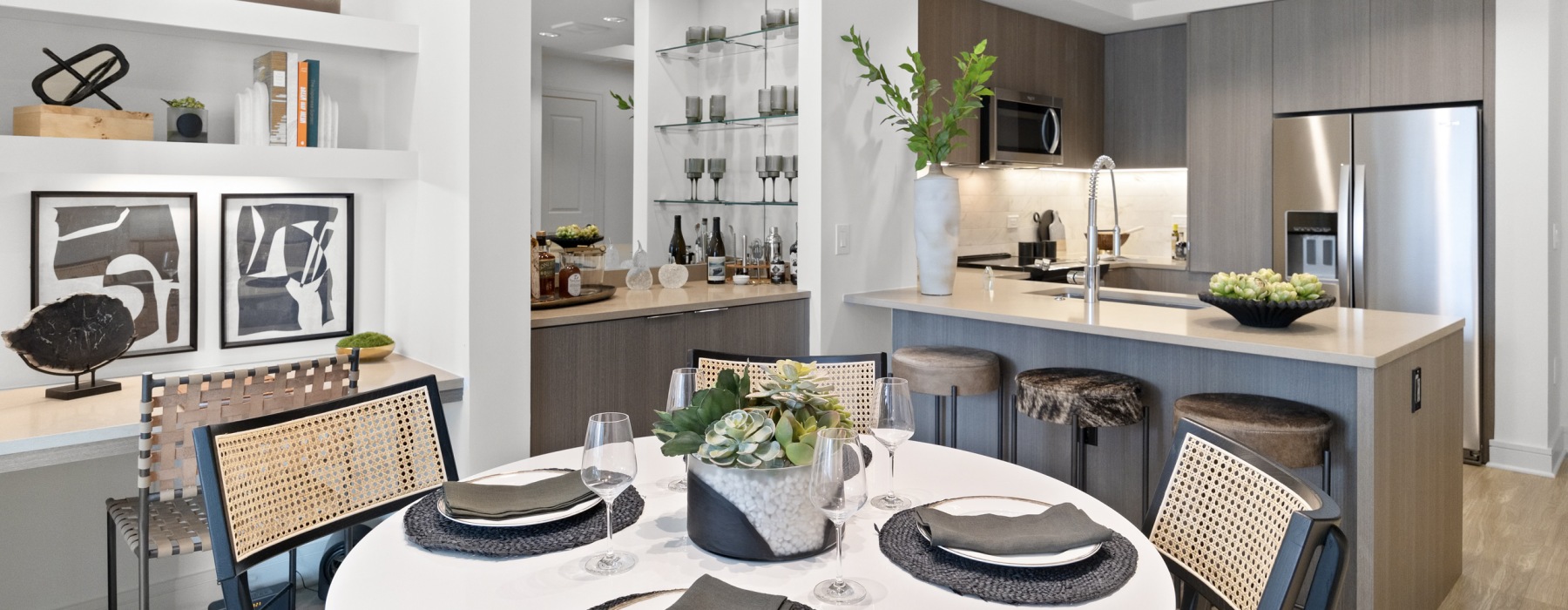 a kitchen with a bar and chairs, dinning table, bookshelf, and dry bar