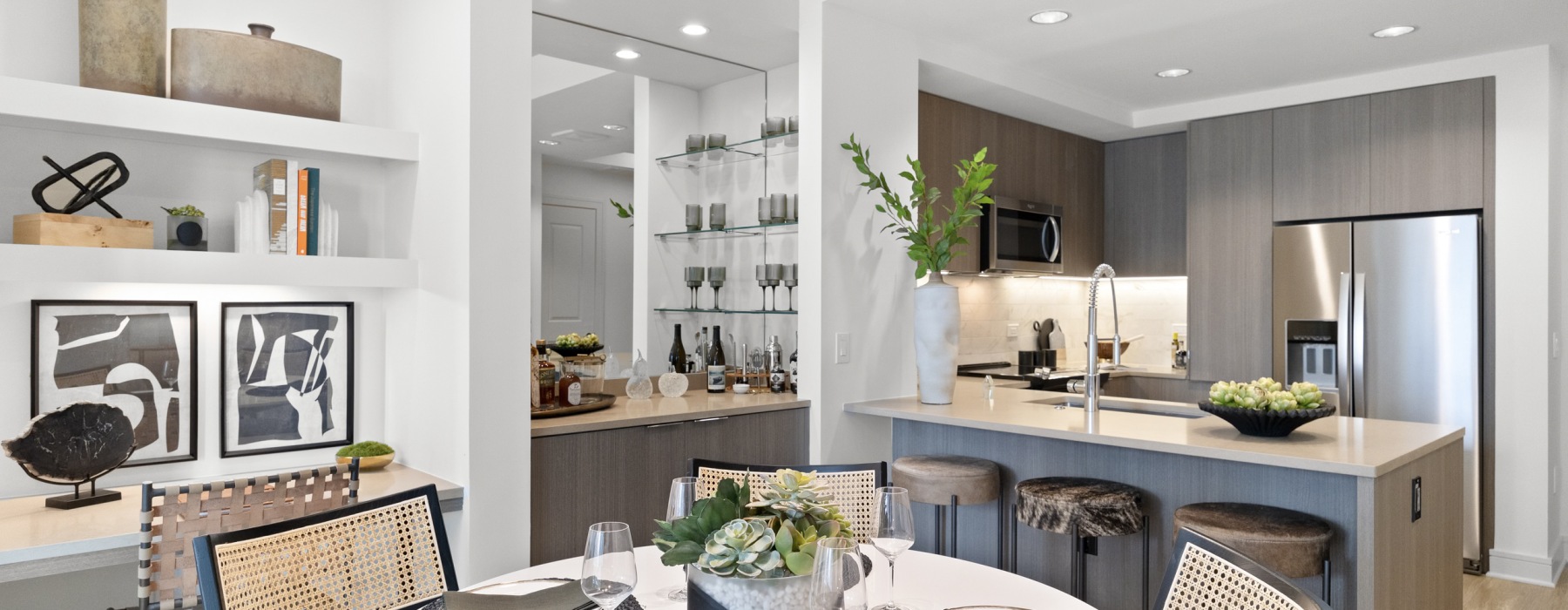 a kitchen with a bar and chairs, dinning table, bookshelf, and dry bar